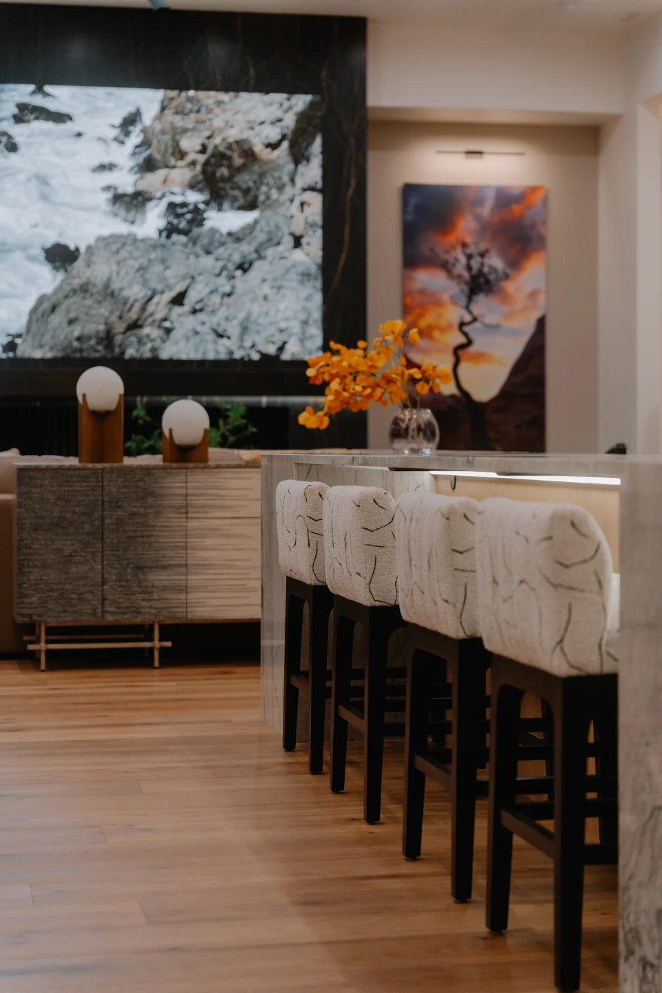 Kitchen island seating with a large media screen visible beyond
