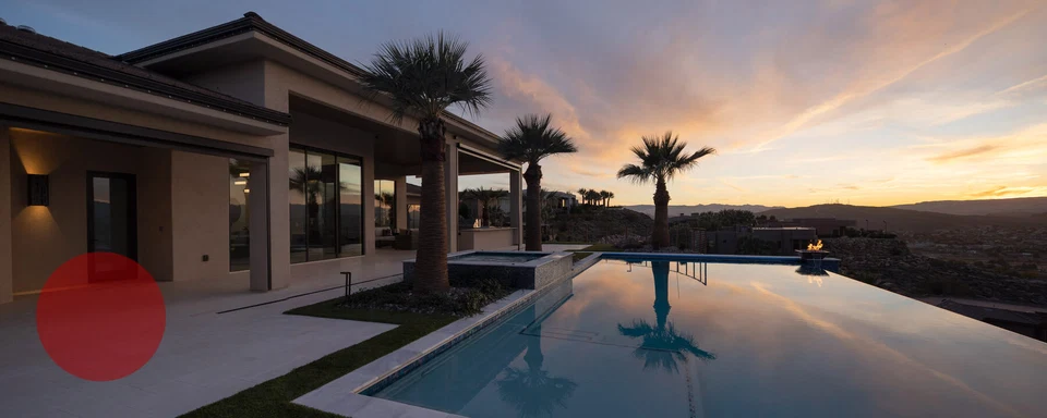 Illuminated covered patio beside an infinity-edge pool at sunset