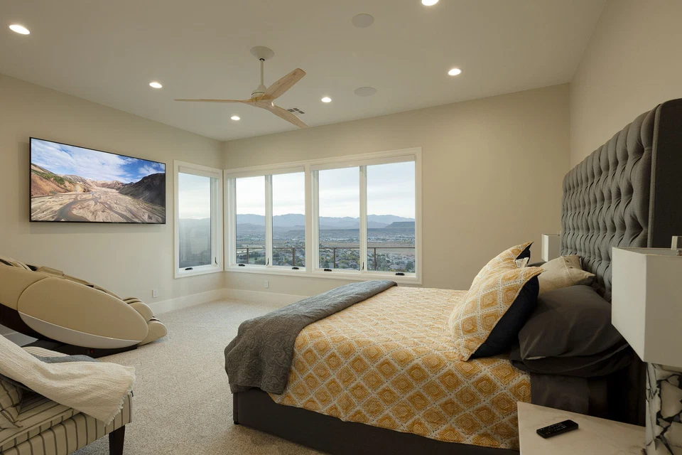 Bedroom with wall-mounted television, ceiling fan, and valley views