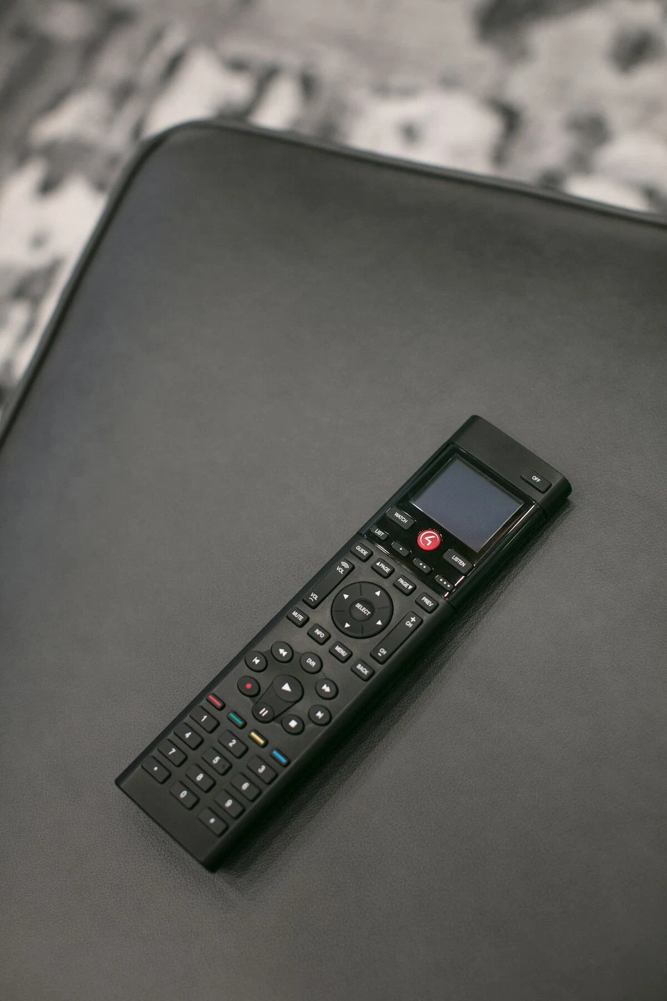 Black media remote resting on a dark upholstered surface