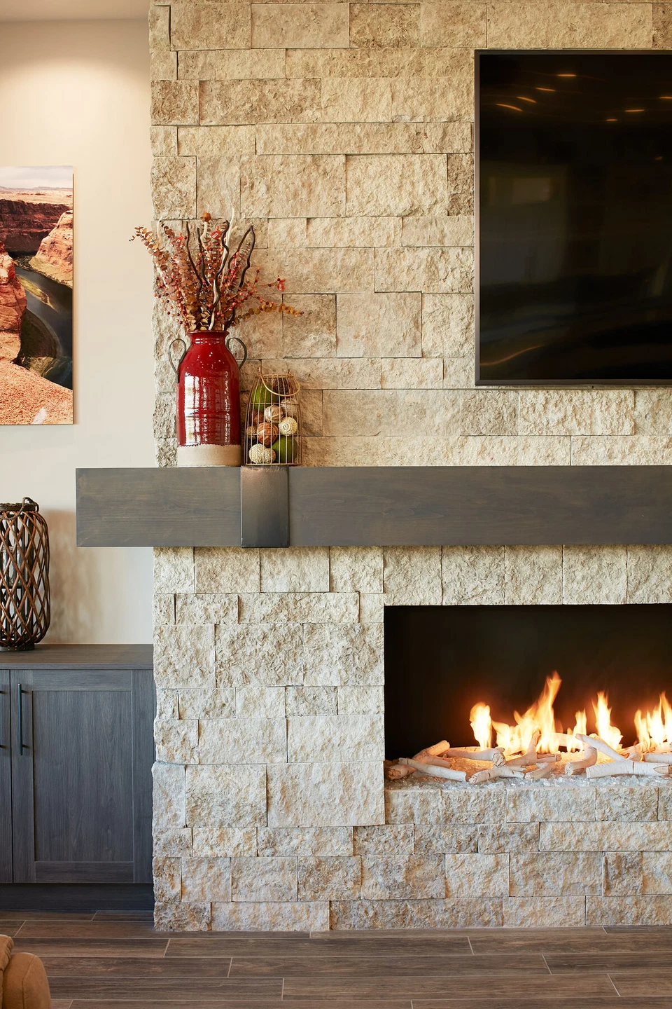 Close view of a linear gas fireplace and television on a stone wall