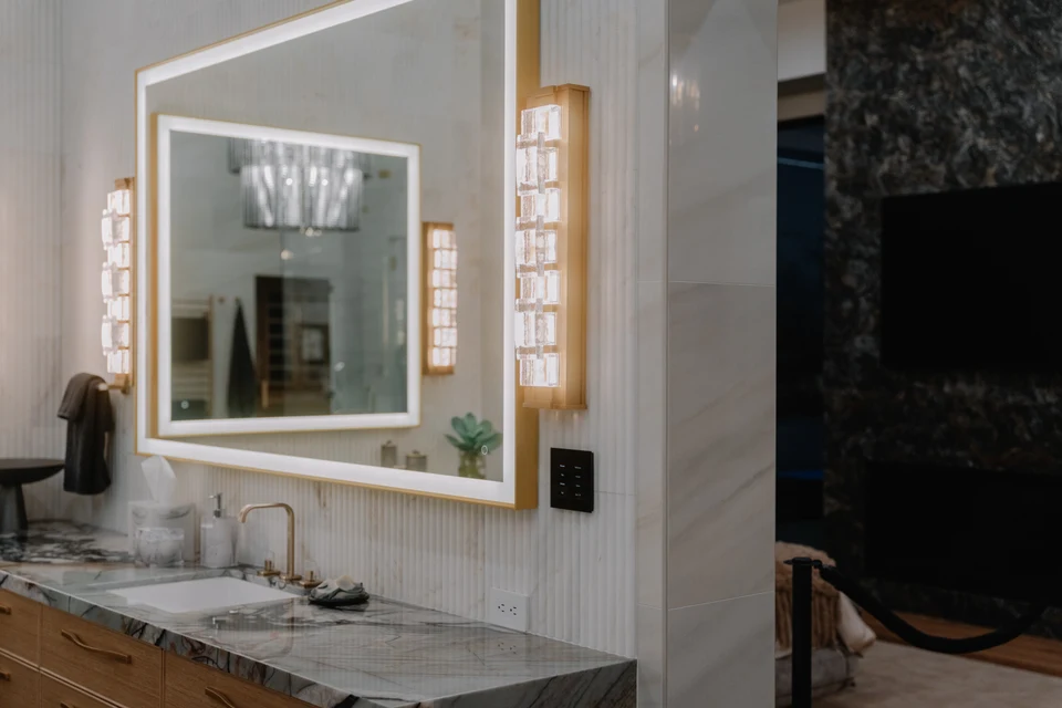 Illuminated vanity mirror and wall keypad beside dark stone tile