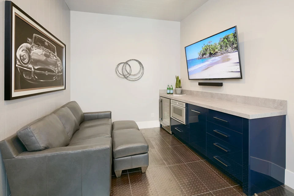 Small sitting room with a gray sofa, wall-mounted television, and blue cabinetry