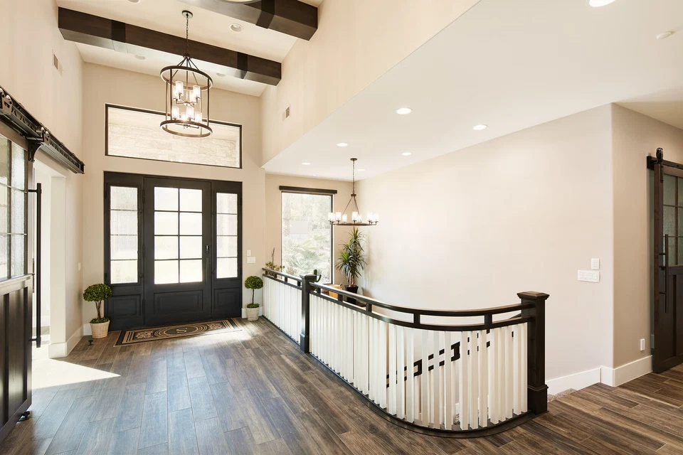 Entry hall with glass double doors, chandelier, and curved stair railing