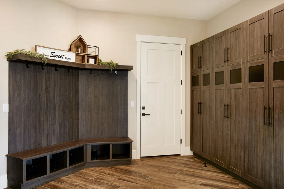 Mudroom bench and tall wood storage cabinets beside an interior door