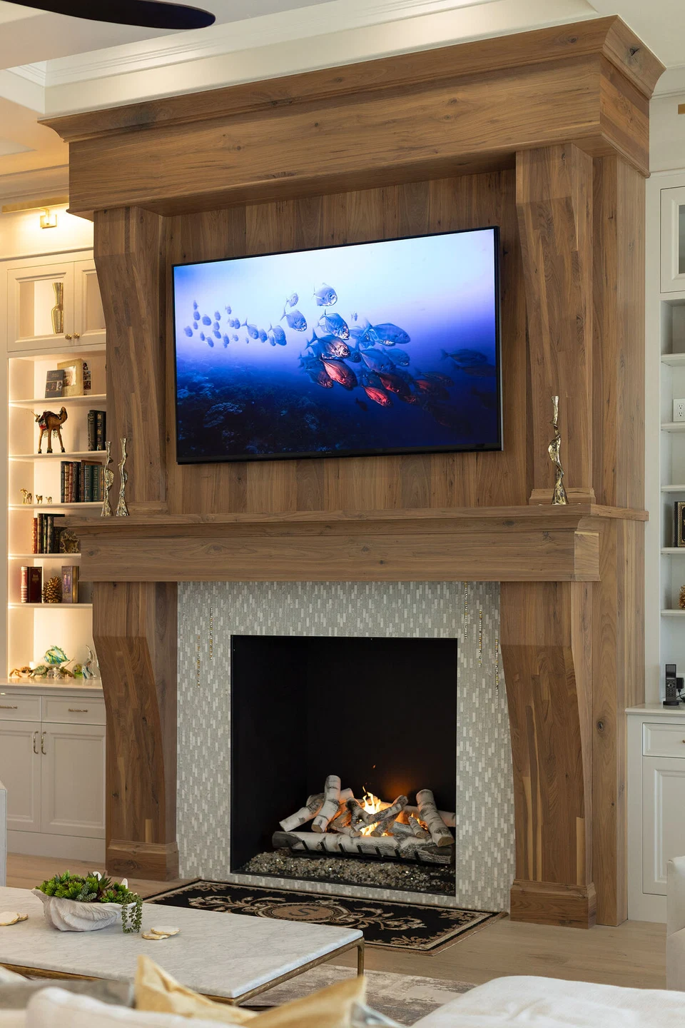 Television above a stone fireplace flanked by built-in display shelves