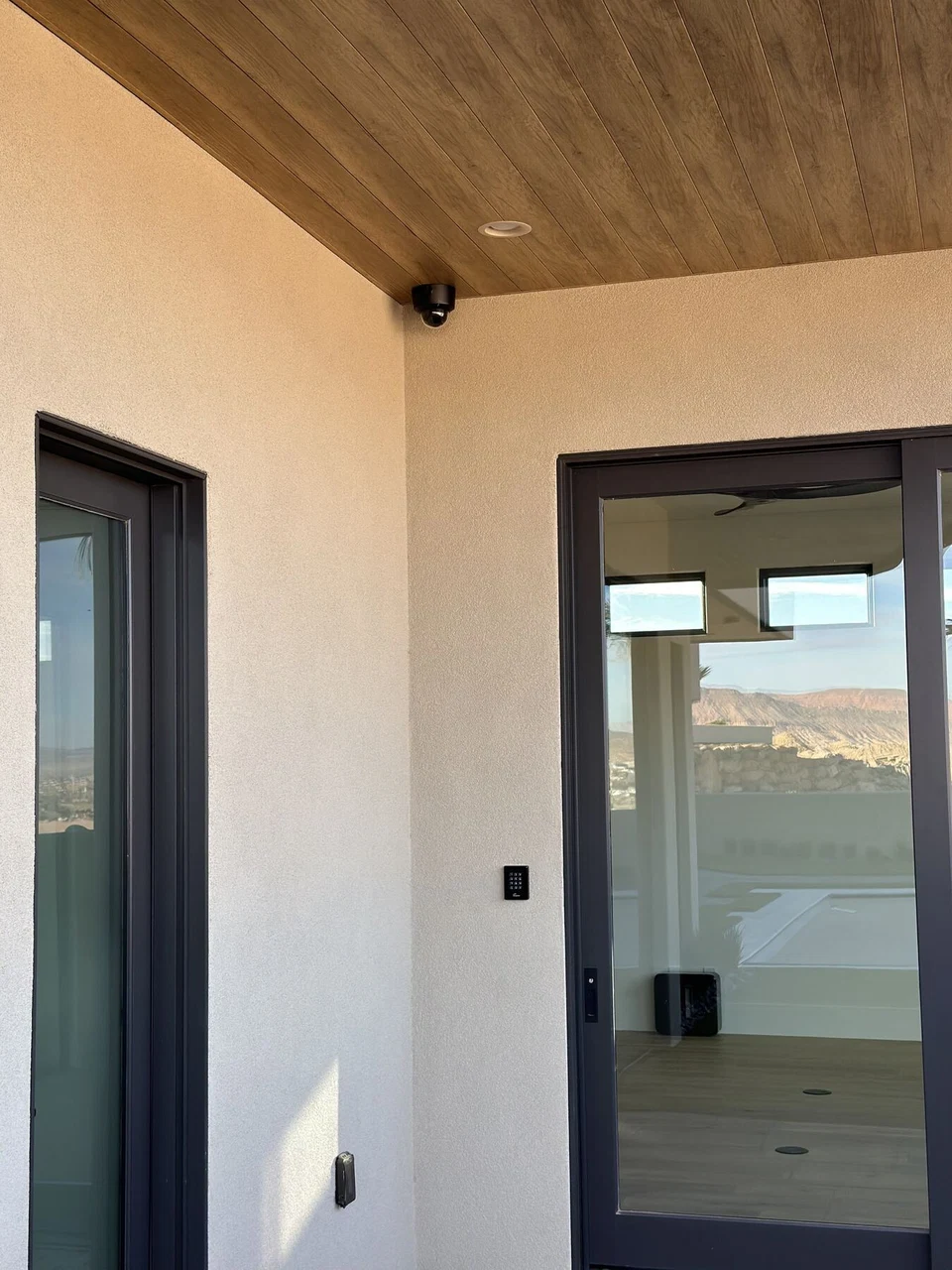 Exterior doorway beneath a wood patio ceiling with a mounted camera