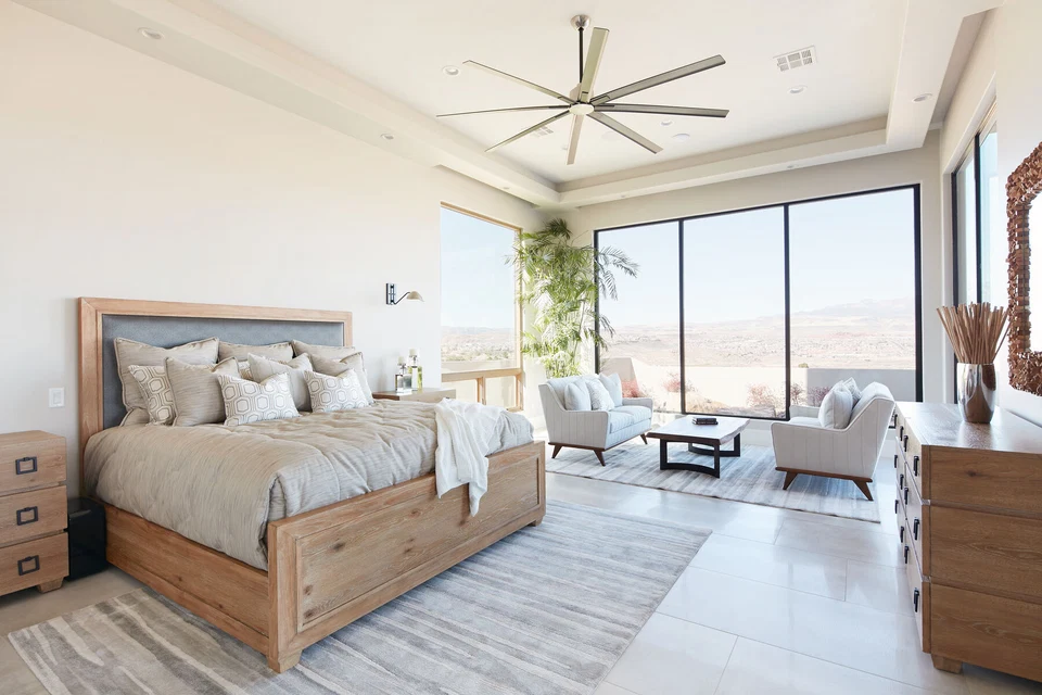 Bedroom with wood bed frame, large ceiling fan, and bright corner windows