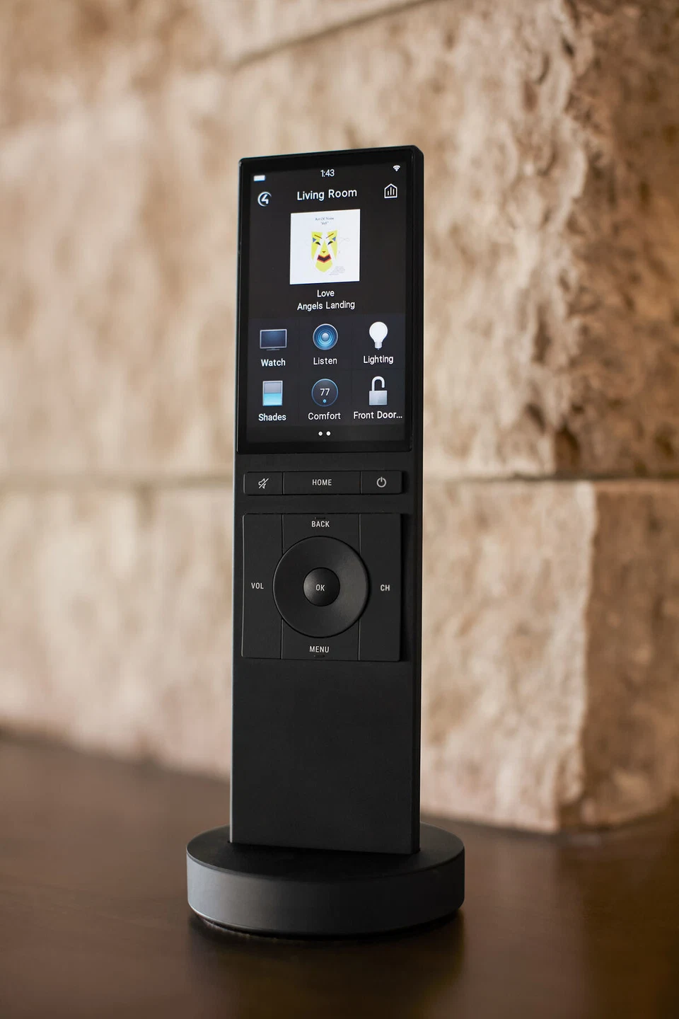 Handheld touchscreen remote in a charging dock against a stone wall