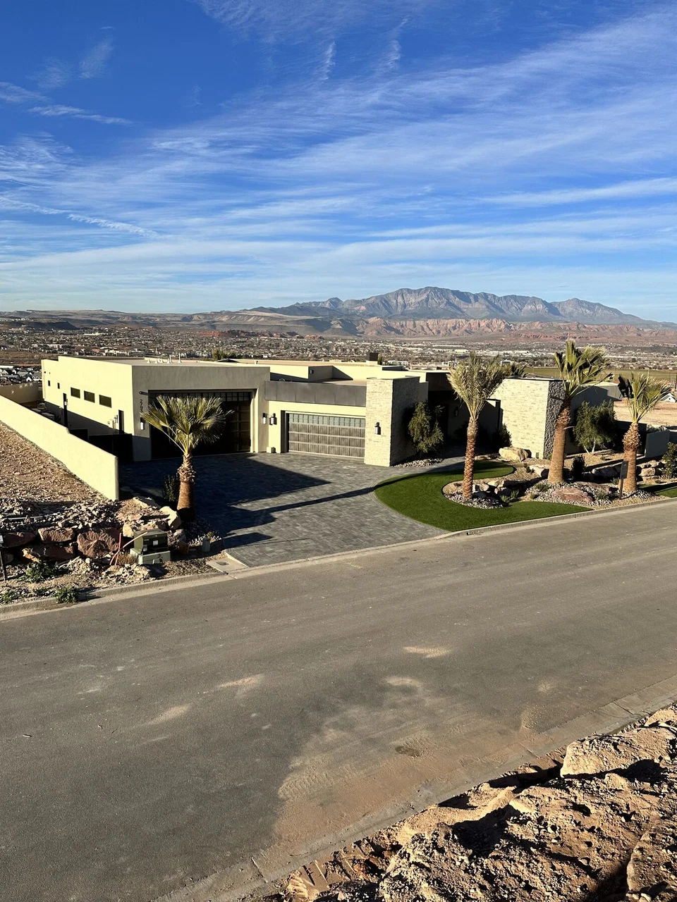 Single-story home exterior across the road with mountains behind