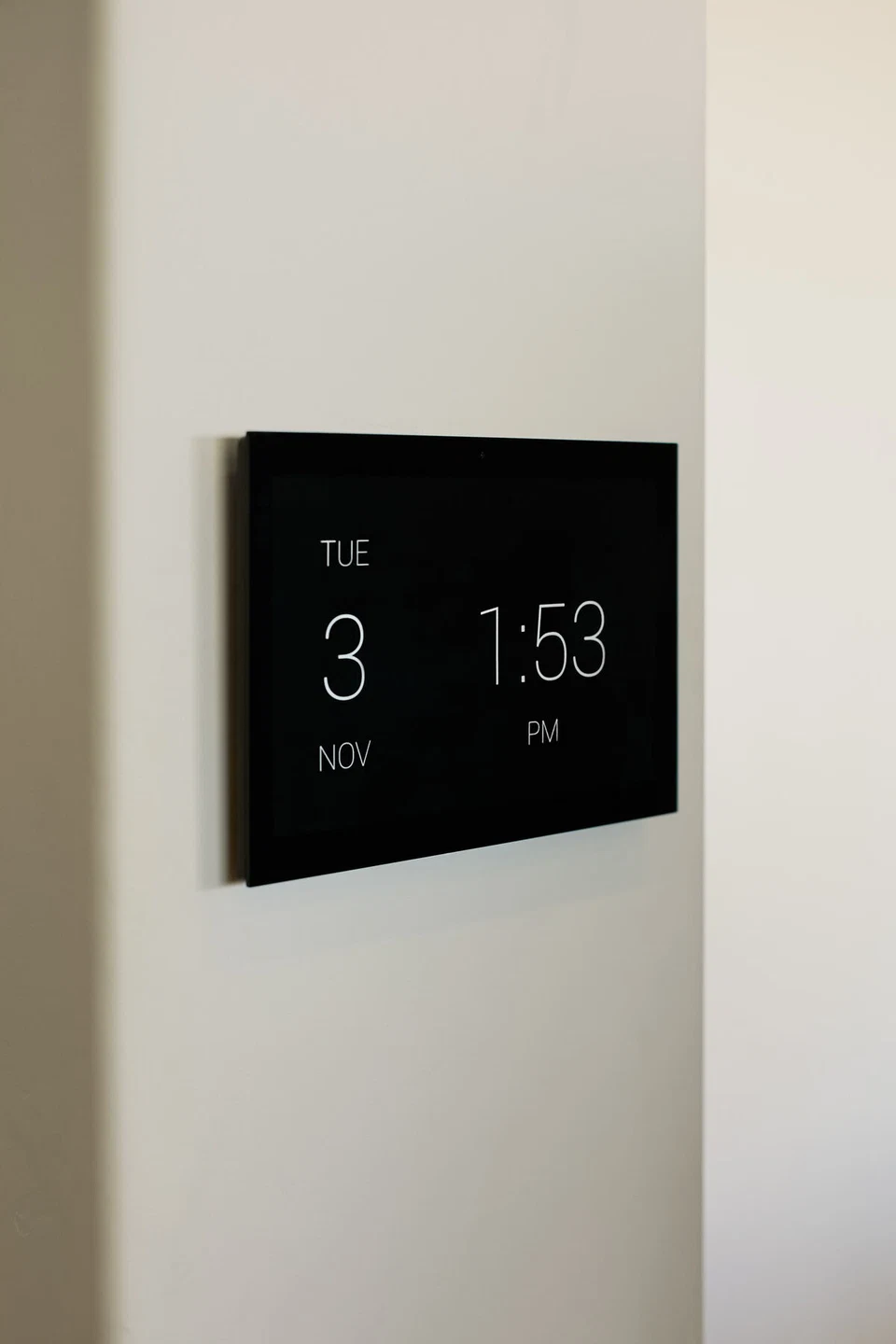 Black wall-mounted touchscreen displaying a clock