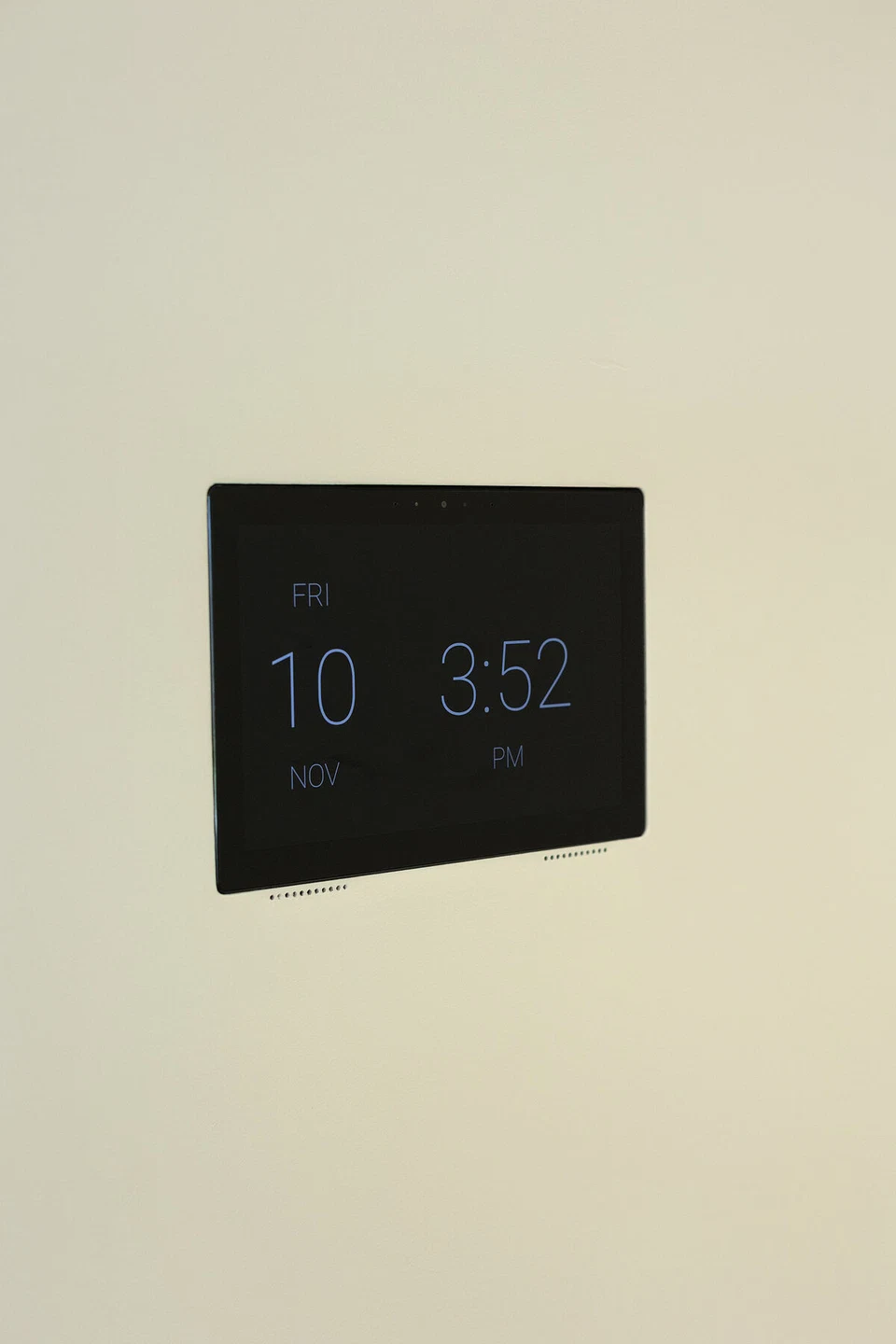Black wall touchscreen displaying a clock on a pale wall