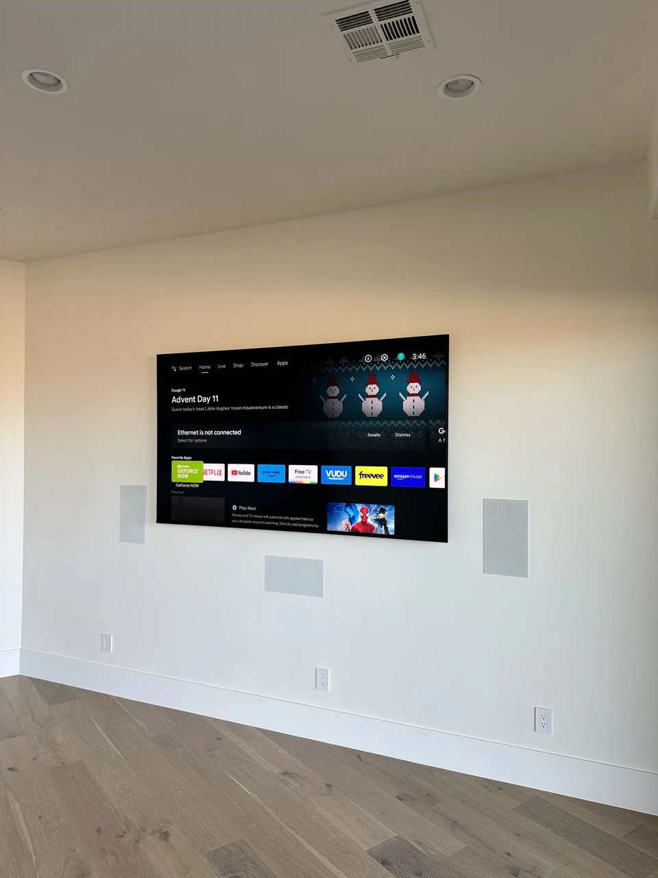 Television displaying a media menu between white in-wall speakers