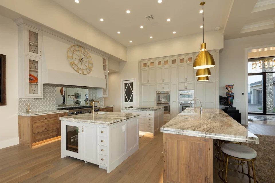 Kitchen with two stone-topped islands and brass pendant lights