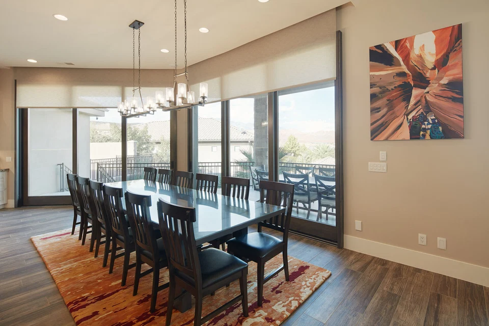 Long dining table beside sliding glass doors under a linear pendant