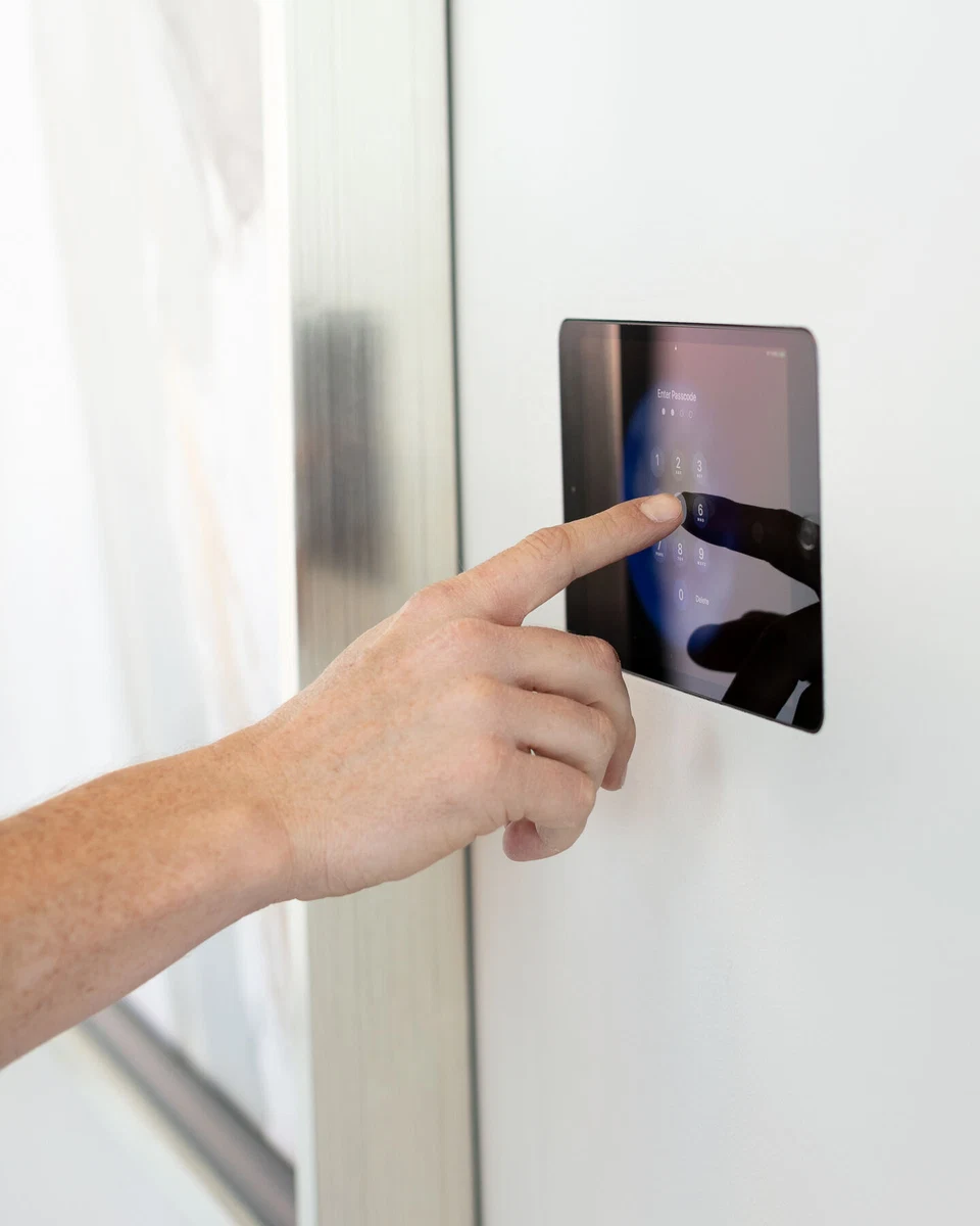 Hand operating a wall-mounted touchscreen beside a curtain
