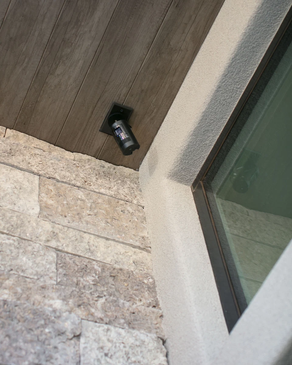 Security camera beneath a wood soffit above an exterior window