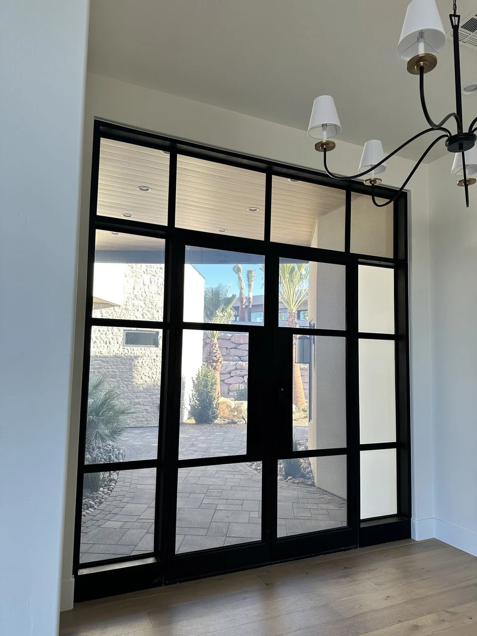 Interior view of black-framed glass doors beside a white wall