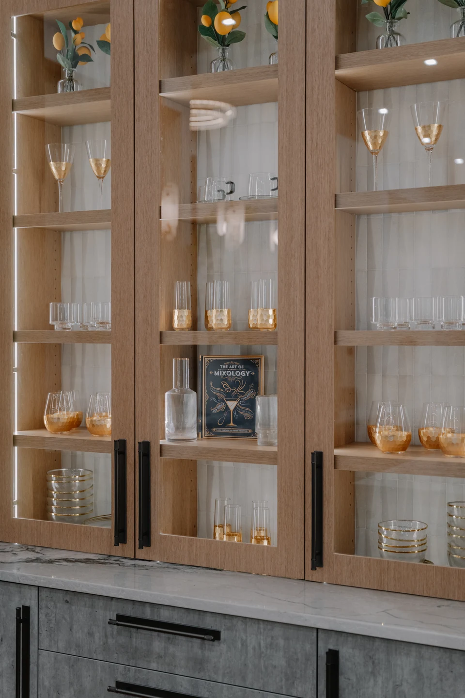 Glassware displayed in tall wood cabinets with illuminated shelves