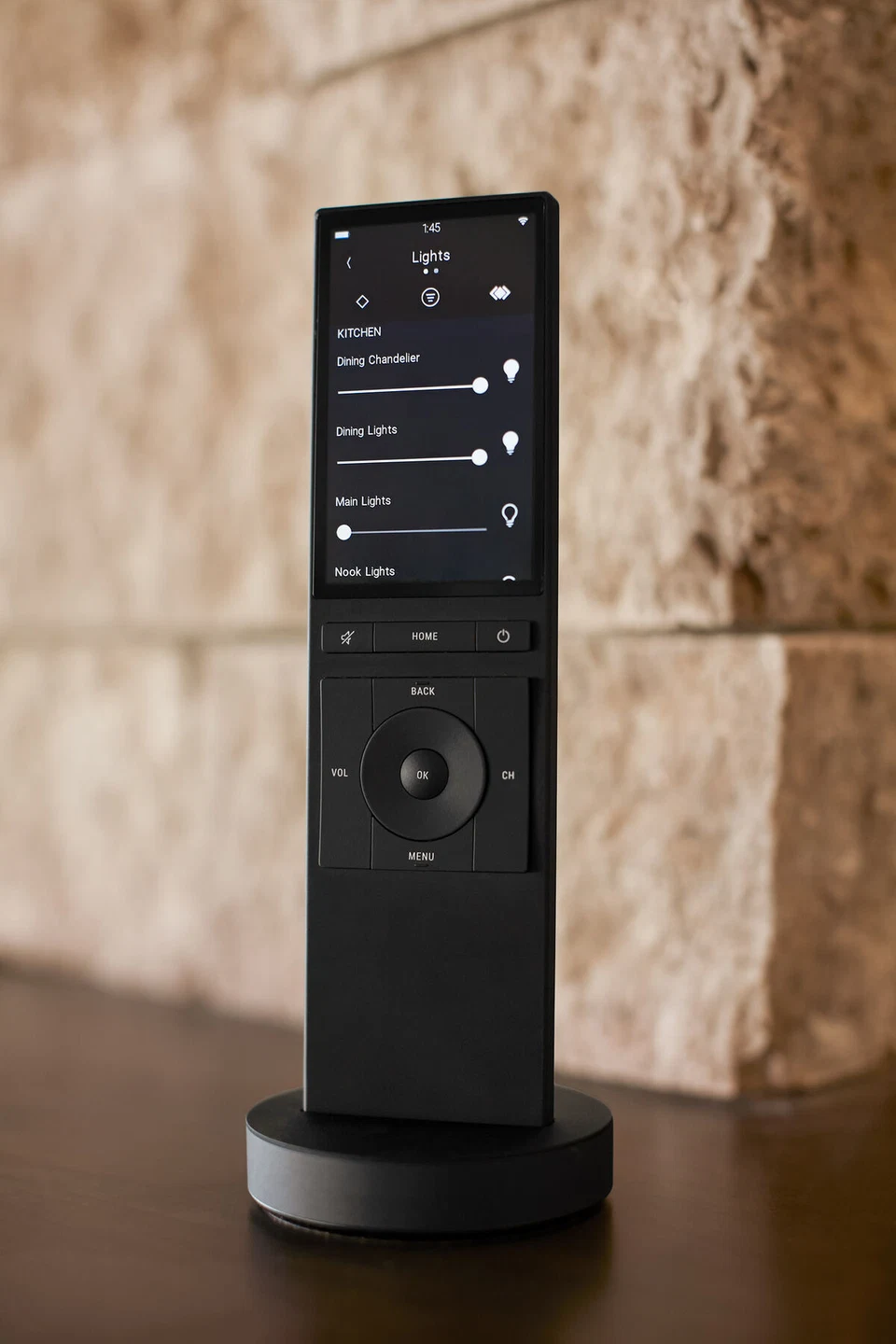 Black media remote showing a settings list against a stone backdrop