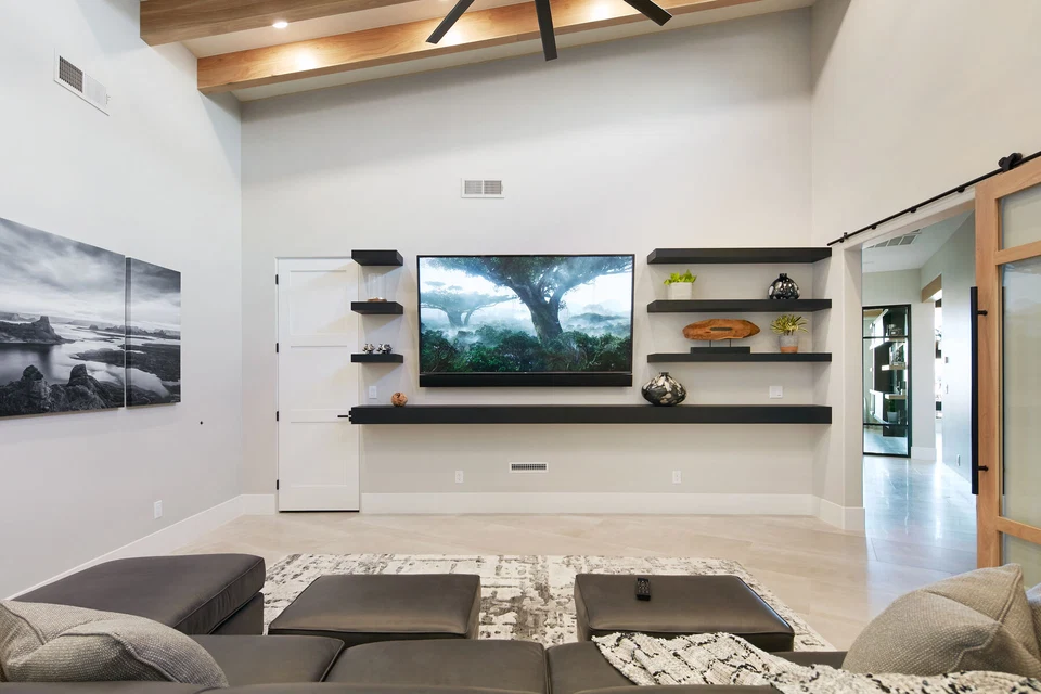 Media room television wall with floating shelves and a low white cabinet