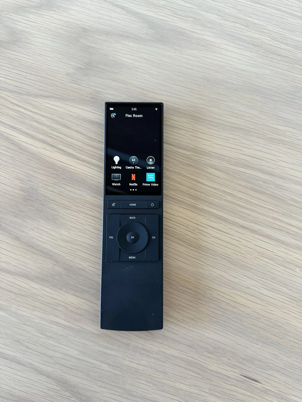 Black handheld touchscreen remote resting upright against a stone surface