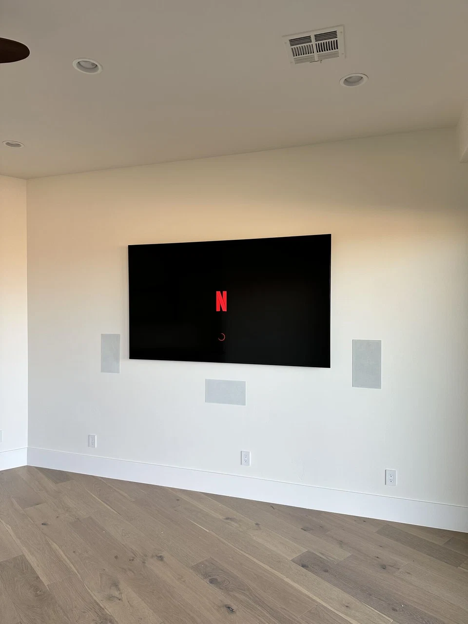 Wall-mounted television and in-wall speakers in an unfurnished room