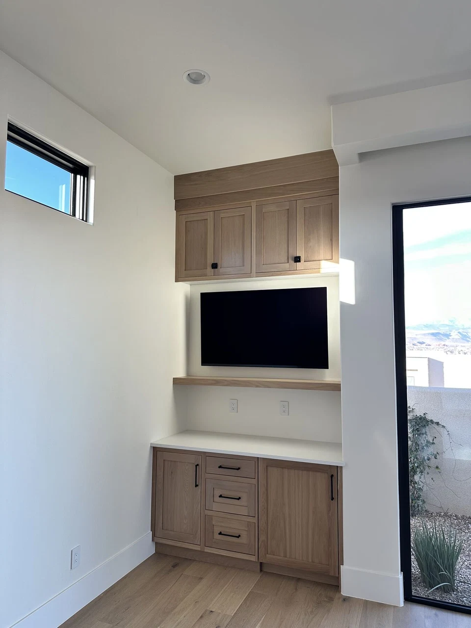 Wall-mounted television between upper and lower wood cabinets