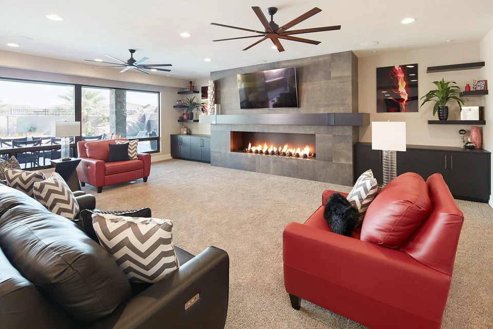 Family room with red armchairs and a television above a linear fireplace
