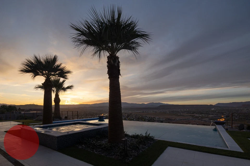 Palm trees silhouetted above the pool and spa at dusk