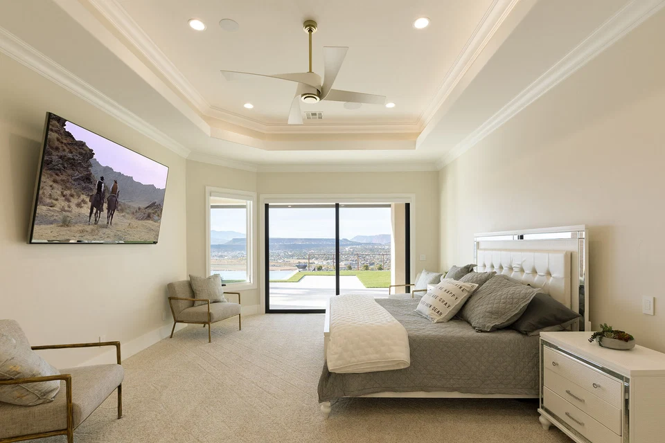 Bedroom with wall-mounted television, tray ceiling, and glass patio doors