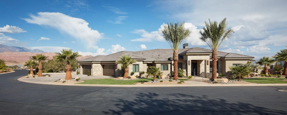 Wide exterior view of a single-story home with stonework and palm trees