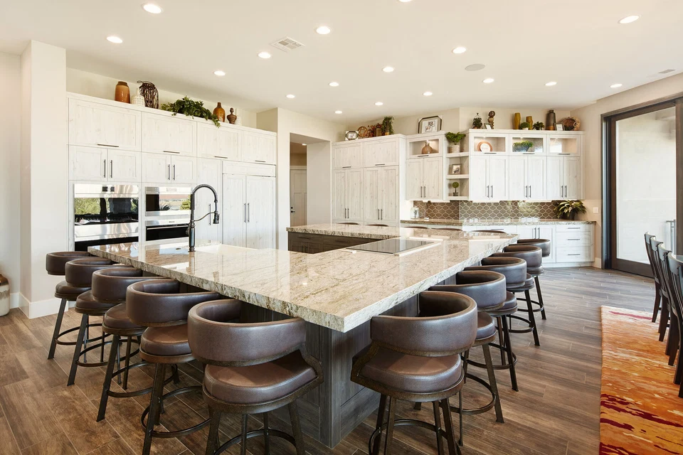 Large kitchen island with bar stools beneath recessed ceiling lights