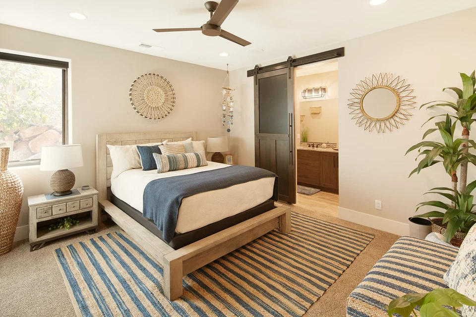 Bedroom with blue bedding, decorative wall mirrors, and a ceiling fan