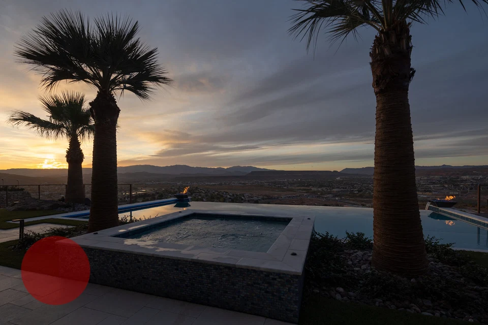 Raised spa and pool framed by palm trees in fading evening light