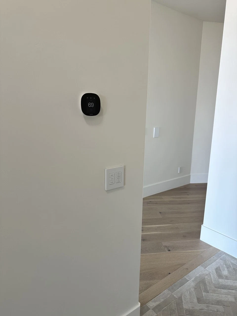 Round black thermostat above a white wall switch