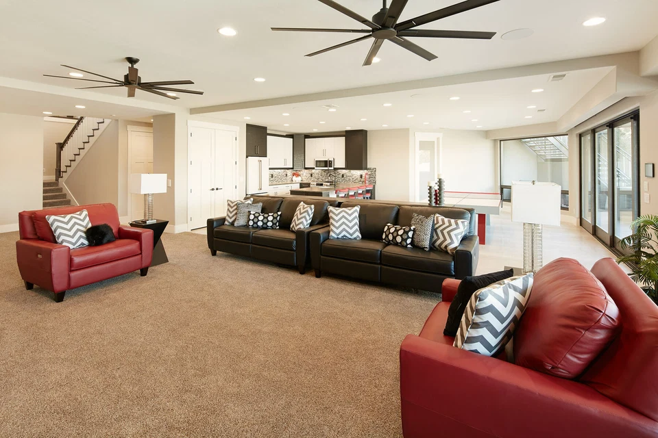 Open family room with sectional sofa, ceiling fans, and adjoining kitchen