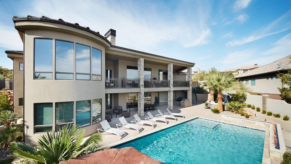 Rear of a two-story home with balconies beside a swimming pool