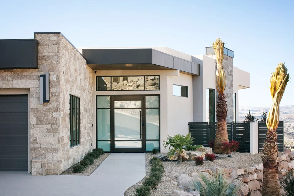 Stone-clad front entrance with glass double doors and desert landscaping