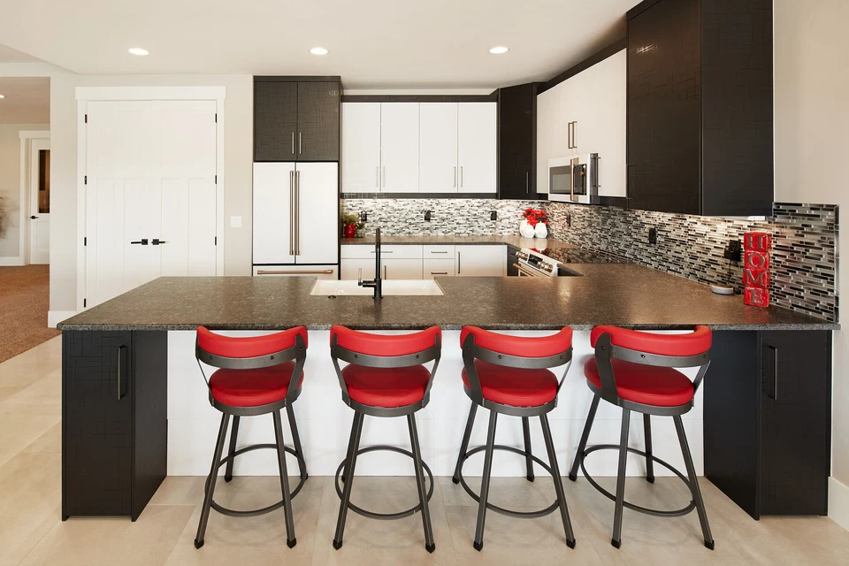 Lower-level kitchen island with red bar stools and dark cabinetry