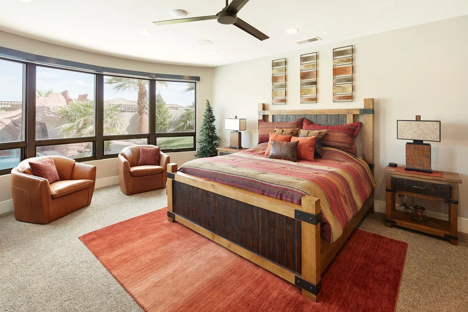 Bedroom with patterned bedding and seating beside large windows