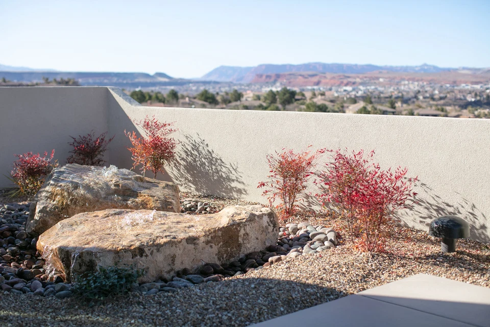 Desert garden with large rocks, red shrubs, and mountain views