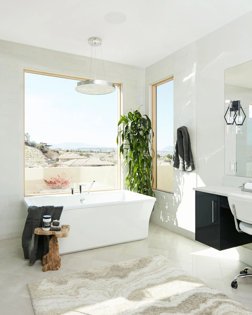 Freestanding white bathtub beneath a large bathroom window