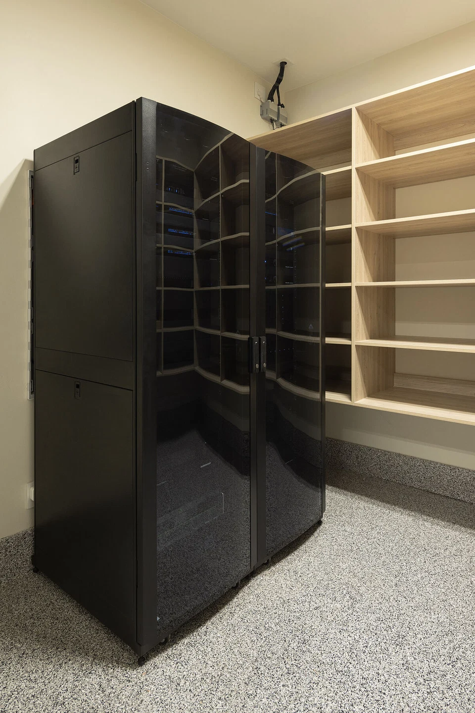 Tall black equipment rack in a closet with open storage shelves