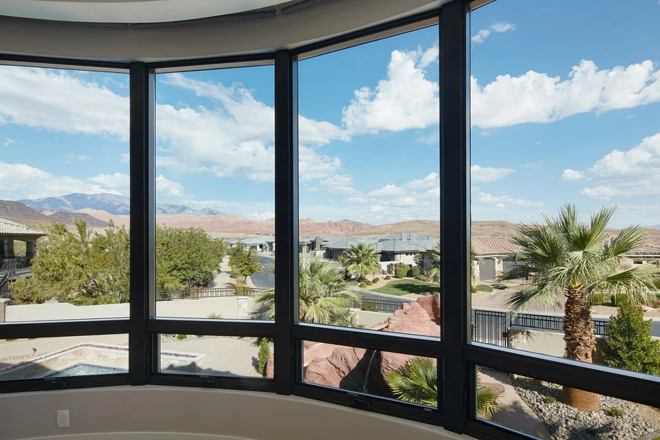 Wide bedroom windows overlooking palm trees and desert hills