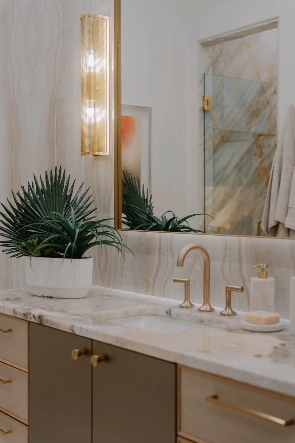 Stone bathroom vanity with brass faucet, wall sconce, and mirror