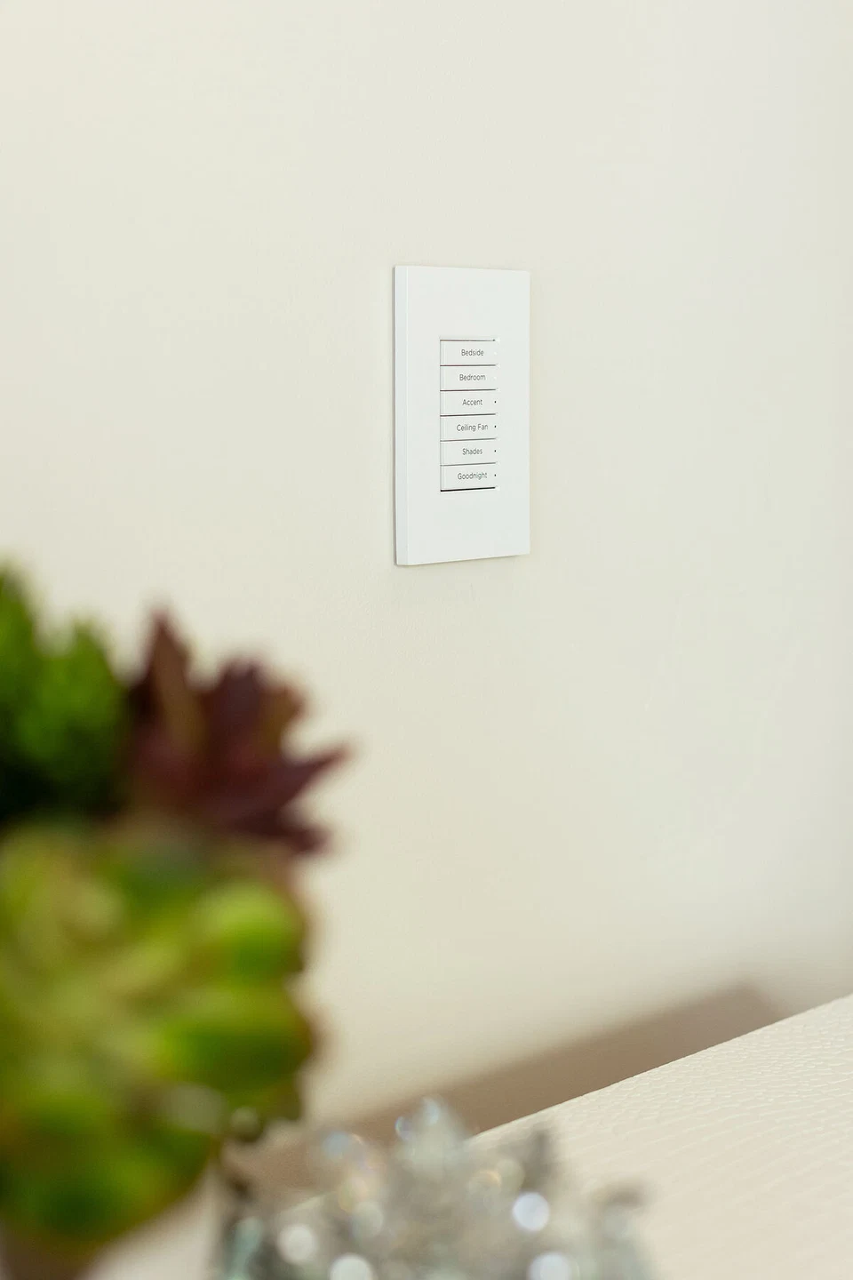 White bedside lighting keypad on a pale bedroom wall