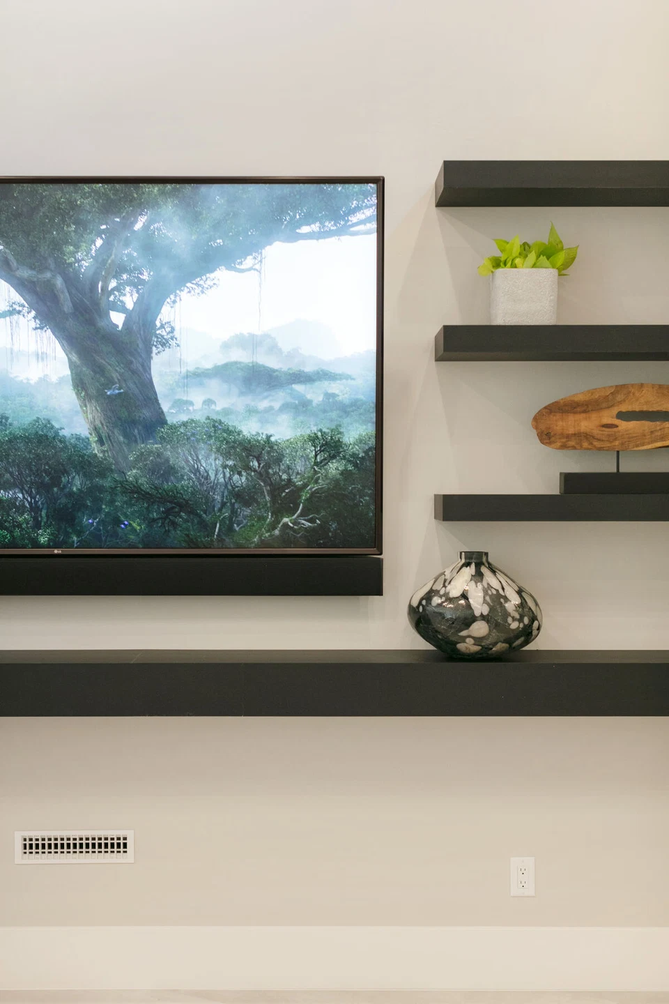 Wall-mounted television beside floating shelves and decorative objects