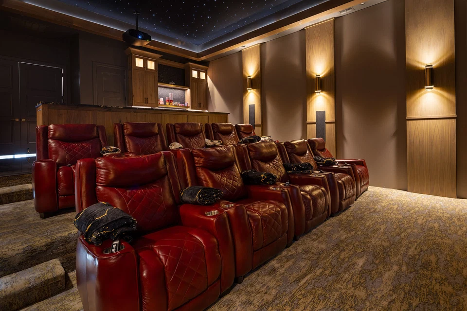 Home theater with rows of red leather recliners and wall sconces