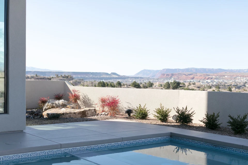 Pool edge beside desert planting beds and a pale boundary wall